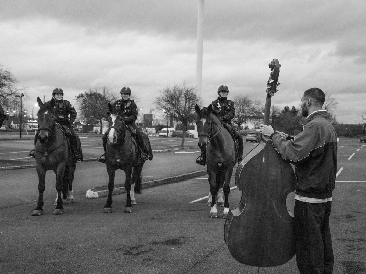 Photo de tournage en noir et blanc, un contrebassiste et des cavaliers
