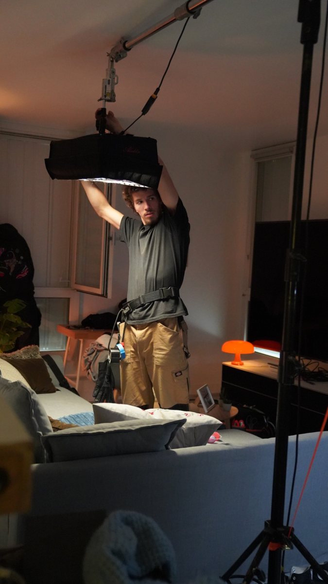Un technicien installe une lumiere sur un tournage en interieur