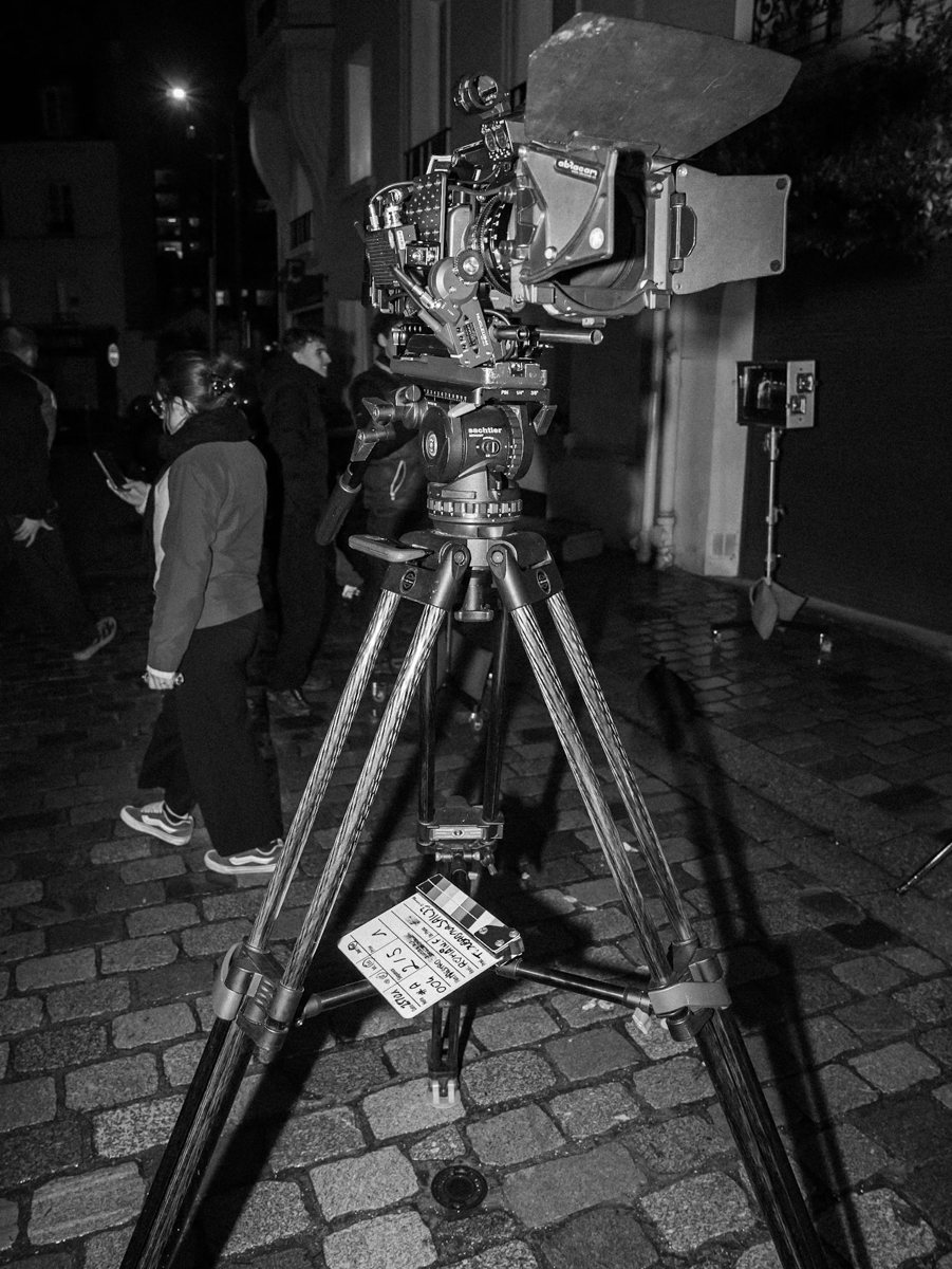 Camera de cinema sur pied dans une rue pavee, de nuit